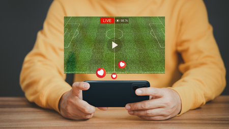 Man using a smartphone or mobile phone for watching live football streaming online on virtual screen, searching video on internet, concept of content online.の写真素材