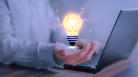 Man holding a abstract light bulb while working on the computer to think and create new ideas with technological innovations and creativity Ideas inspired by online technology, innovations.の写真素材