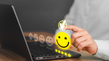 Male hand using a laptop computer with pop-up smile face five star icon for service reviews, satisfaction and testimonials. Customer Service Experience and Business Satisfaction Surveys.の写真素材