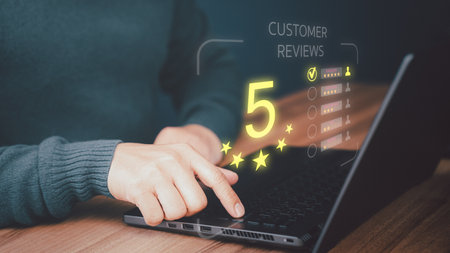 Businessman hand using computer laptop with popup five star icon for feedback review satisfaction service, testimonial. Customer service experience and business satisfaction survey.の写真素材