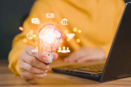 Man holding a light bulb while working on the computer to think and create new ideas. Business global internet connection application technology and digital marketing, Financial and banking.の写真素材