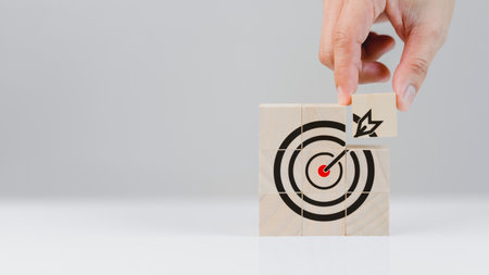 Hand put a goal icon on wooden cube block on wood table. Business growth and goal in next year concept.の写真素材