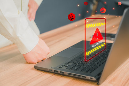 Personal computer virus detected, user data protection, network security and maintenance concept. Man using computer laptop with triangle caution warning sign for notification error.の写真素材