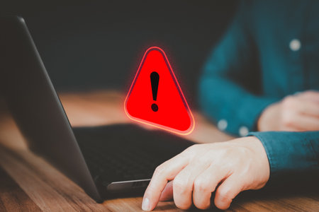 Adult man using a computer laptop with triangle caution warning sign for notification error. Concept technology of computer virus detected, personal data protection, network security and maintenance.の写真素材