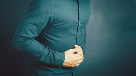 Young man with hand on stomach because nausea, painful disease feeling unwell. Stomachache concept.の写真素材
