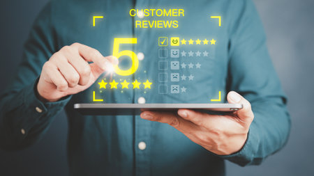 Man hand using a tablet with pop up smiley face and five star icon for assessment feedback review satisfaction and testimonial. Customer service experience and business satisfaction survey.の写真素材