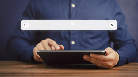 Adult man hand working with a tablet on the desk in office. Searching browsing internet data information with blank search bar. Search engine optimization SEO networking concept.の写真素材
