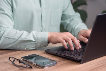 Closeup image of a young man working and typing on laptop computer keyboard on wooden table in the cafe.の写真素材