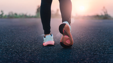 Young woman doing exercise walking on country road in the morning with sunrise background, concept...