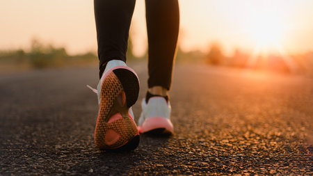 Young woman doing exercise walking and run on country road in the morning with sunrise background, concept of health and lifestyle.の写真素材