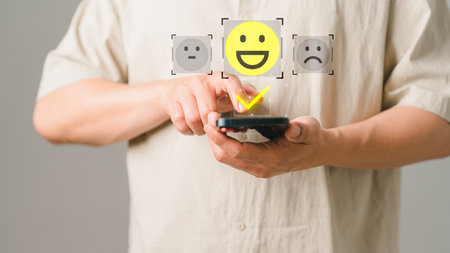 Man hand using a mobile phone with popup smile face icon for feedback review satisfaction service and testimonial. Customer service experience assessment and business satisfaction survey.の写真素材