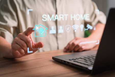 Iot smart home automation app concept. Adult man controlling technology AI smart home devices using a laptop computer with launched application in the bed room.の素材