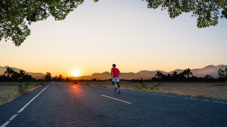 Young asian fitness man running and jogging outdoors on the road for exercise, cardio workout and marathon training in the morning countryside.の写真素材
