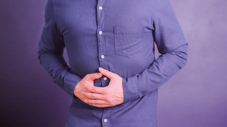 Young man with hand on stomach because nausea, painful disease feeling unwell. Stomachache concept.の写真素材