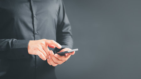 Man viewing website social network connecting with wifi in home by mobile phone. Male hands holding a smartphone model touching sensor screen to browse internet. Concept of Virtual communication.の写真素材