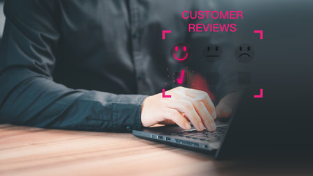 Man hand using a computer laptop with pop up smiley face icon for assessment feedback review satisfaction opinion and testimonial. Customer service experience and business satisfaction survey.の写真素材