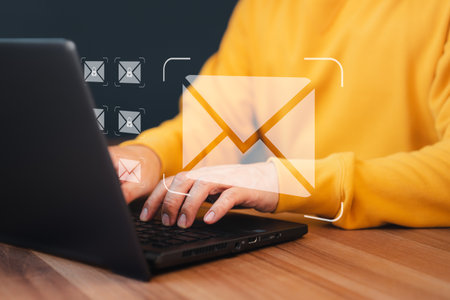 Concept of Email marketing, send e-mail or news letter, online working internet network. Man hand using computer laptop typing on keyboard and surfing the internet on office table with email icon.の写真素材