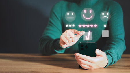 Customer service experience assessment and business satisfaction survey. Man hand using a mobile phone with popup smile face icon for feedback review satisfaction service opinion and testimonial.の写真素材