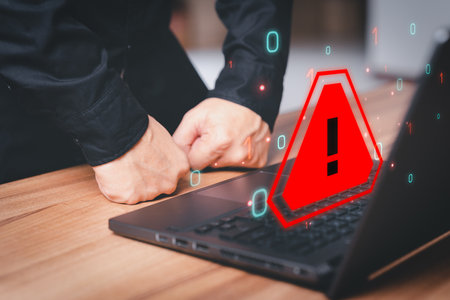 Man working on computer laptop with triangle caution warning sign for notification error. Technology and maintenance concept of computer virus detected, network security and personal data protection.の写真素材