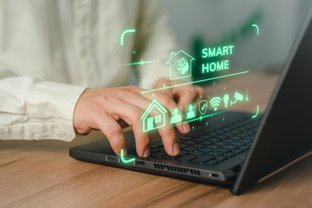 Adult man controlling technology AI smart home devices using a laptop computer with launched application in the bed room. Iot smart home automation app concept.の写真素材