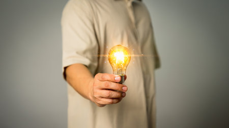 Adult man hand holding illuminated light bulb, creative with brain icon. Inspiration concept of learning, new knowledge and sustainable business development, innovation and inspiration idea.の写真素材