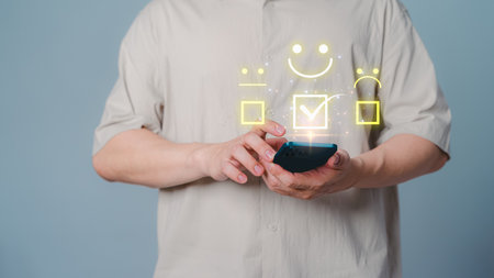 Client hand using a mobile phone with pop up smile face icon for feedback review satisfaction service opinion and testimonial. Customer service experience assessment and business satisfaction survey.の写真素材