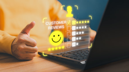 User hand using a computer laptop with pop up smiley face and five star icon for assessment feedback review satisfaction and testimonial. Customer service experience and business satisfaction survey.の写真素材