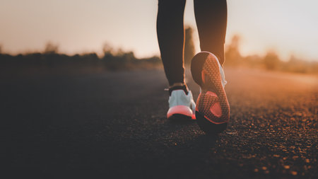 Young woman doing exercise walking and run on country road in the morning with sunrise background, concept of health and lifestyle.の写真素材