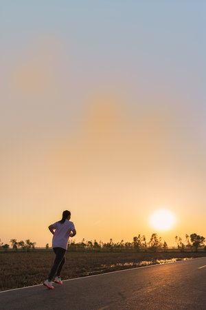 Young asian fitness woman jogging and running outdoors on the road in the morning for a healthy lifestyle.の写真素材
