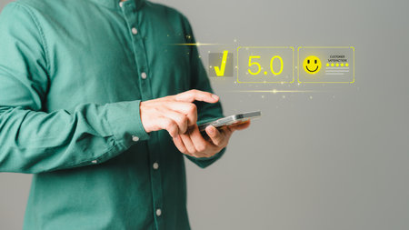 Customer using a mobile phone to rate service satisfaction with virtual screens on smile face icon. Comment scores are very impressive. Customer service assessment, testimonial, and feedback.の写真素材
