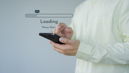 Young man using a mobile phone for download and update application and waiting to loading digital file data form the apps, very slow internet form wifi. Concept of waiting for load of loading symbol.の写真素材