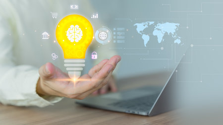 Business and Technology Concepts: Innovative Ideas, AI, and Light Bulb on Hand. Man working on a computer laptop to think and generate new ideas through technological innovation and creativity.の写真素材