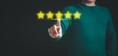 Customer hand touching the stars to complete five stars. Comment scores are good. Customer service assessment, testimonial, feedback, giving a five star rating. Service rating, satisfaction concept.の写真素材