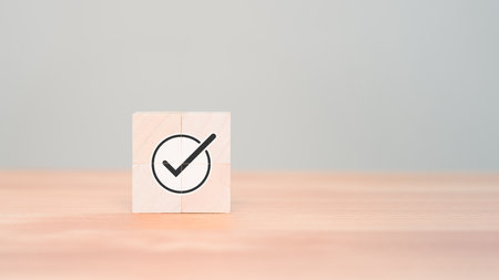 Wooden cube with checkmark icon on wood table. Goals achievement and business success. Quality and ISO symbol. Do the right thing. Tick and cross signs, approve and disapprove symbol.の写真素材