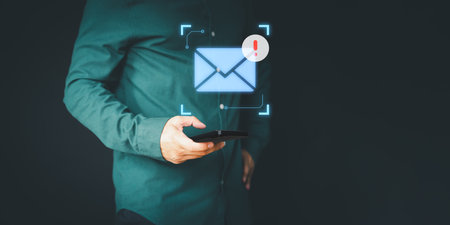 Male hand using a mobile phone with an email icon, Email alert with a caution warning sign for notification error. Security protection on the internet, junk mail, and compromised information.の写真素材