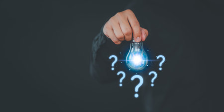 Male hand holding glowing light bulb with question mark. Business concept of no ideas, work hard,...