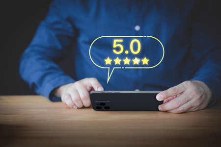 User hand using a mobile phone with pop up five stars icon for feedback review satisfaction service opinion and testimonial. Customer service experience assessment and business satisfaction survey.の写真素材