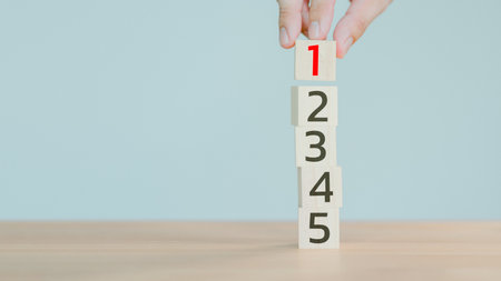 Hand putting a wooden cube with number 1 on wood cube stack alphabet 2 3 4 5 on wood table. Arrange to do list, Task priority, management and business important planning concept.の写真素材