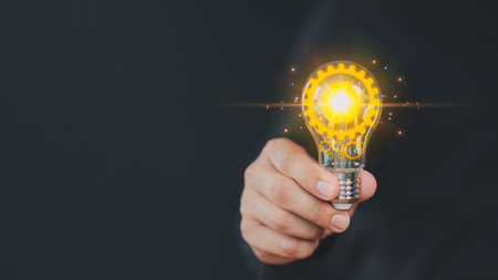 Hand holding illuminated light bulb, copyspace. Creative idea, new business plan, motivation, innovation, inspiration. Energy saving light bulb. Concept of new ideas with innovation and creativity.の写真素材