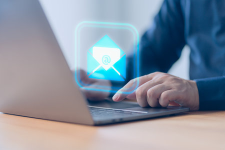 Concept of Email marketing, send e-mail or news letter, online working internet network. Male hand using a computer laptop typing on keyboard and surfing the internet on office table with email icon.の写真素材