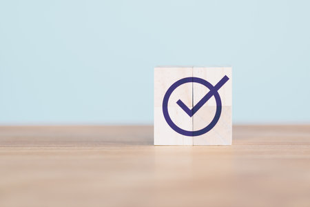 Wooden cube block with checkmark icon on wood table. Goals achievement and business success. Quality and ISO symbol. Do the right thing. Tick and cross signs, approve and disapprove symbol.の写真素材