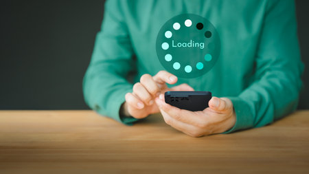 Young man using a mobile phone for download and update application and waiting to loading digital file data form the apps, very slow internet form wifi. Concept of waiting for load of loading symbol.の写真素材