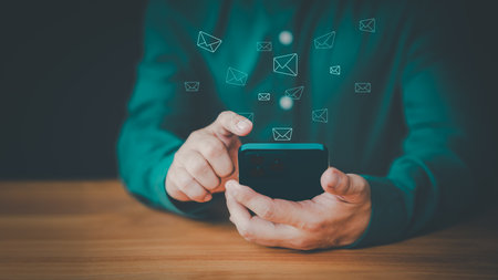 New email notification concept for business e-mail communication and digital marketing. Man using a mobile phone with sending online message with email icon. Inbox receiving electronic message alert.の写真素材