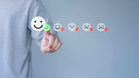Male hand touching the virtual screen on happy smile face icon to give satisfaction in service. Online review concept of assessment testimonial customer service and feedback, Opinion rating very good.の写真素材