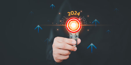 Businessman holding a light bulb with goal icon and the year 2024. Concept of 2024 business planning and strategy innovative business vision and new year resolution target, save energy efficiency.の写真素材