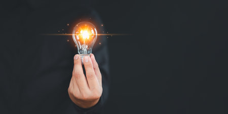 Hand holding illuminated light bulb, copyspace. Creative idea, new business plan, motivation, innovation, inspiration. Energy saving light bulb. Concept of new ideas with innovation and creativity.の写真素材