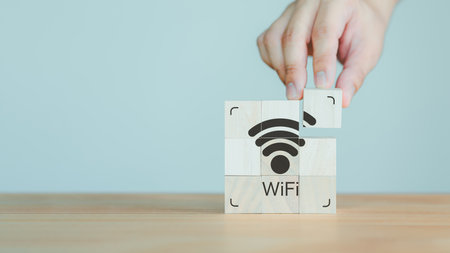 Hand put a wifi icon on wooden cube on wood table. Wifi icon on wooden cube block for service in the cafe. Business communication social network, Wireless network and connection technology concept.の写真素材