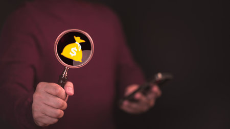 Male hand hold magnifying glass over money bag icon .Concept of search for business and financial, find investment funds for business project. Profitable deposit or loan terms and conditions.の写真素材