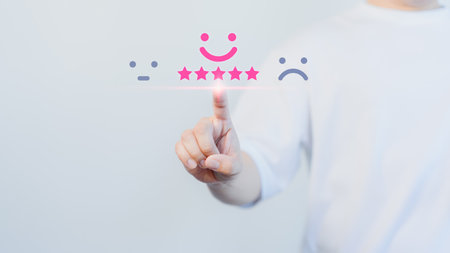 Hand touching the virtual screen on happy smile face icon to give satisfaction in service. Online review concept of customer service, assessment, testimonial and feedback, Opinion rating very good.の写真素材