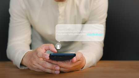 Man holding a smartphone and viewing messages on his mobile phone. Fake Text message SMS scam or fraud concept.の写真素材
